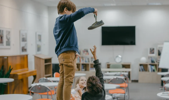 student holding shoe over another student to bully