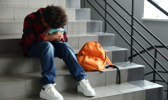 student sitting on stairs with head down looking upset